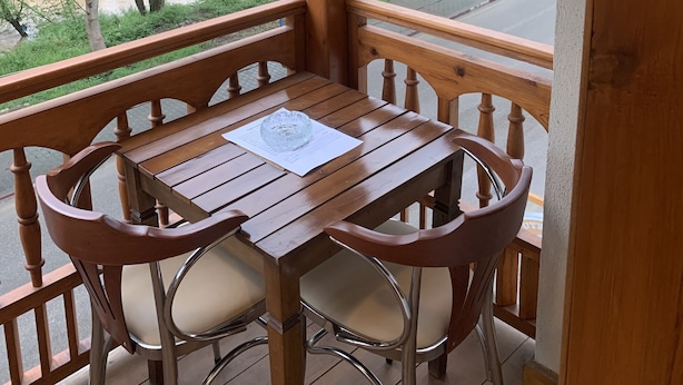 A wooden balcony with a table and chairs, overlooking a river and greenery. - Utku Konağı (Bartin)