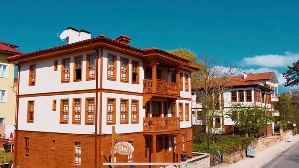 A multi-story hotel with a balcony on the second floor, a sign indicating it is a hotel, and a view of the surrounding neighborhood.