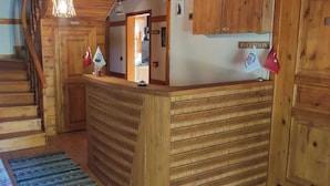 A wooden reception desk with a sign labeled "RECEPTION" and a staircase leading to another room. - Utku Konağı (Bartin)