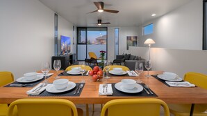 A dining area with a wooden table set for six, yellow chairs, and a view of a cityscape through large windows. - 4 Bed Penthouse w/City View Deck and Firepit. Near Zoo (San Diego)