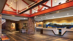 Eine großzügige Lobby mit einer Rezeption, einer Treppe und einer Steinwand.