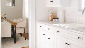 A modern bathroom with white cabinetry, a sink, and a mirror.
