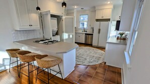 A modern kitchen with a central island, bar stools, and a large window.