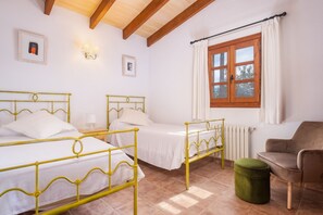A room with two beds, a chair, a radiator, and a window with curtains. - Majorca holiday rental - Villa Joana (Pollensa / Pollença)