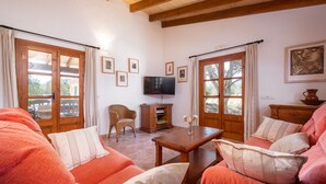 Ein gemütliches Wohnzimmer mit einer Sofagarnitur, Holzmöbeln, einem Fernseher und gerahmten Bildern an den Wänden.