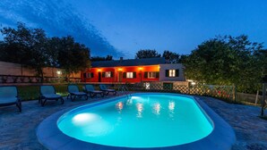 Una piscina con deck de baldosas y sillas de descanso.