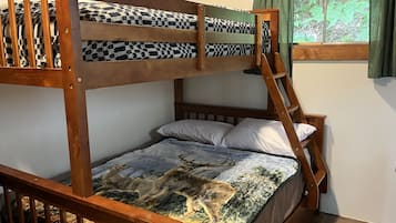 Un lit superposé avec une échelle, des oreillers blancs et une couvre-lit à motifs.