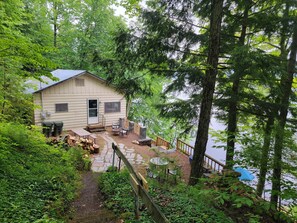 A cabin with a deck, outdoor seating, and a staircase leading to a dock. - Waterfront Location. Panoramic Views. Swimming. Treehouse Tranquility. Private.  (Colton)
