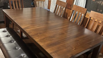 Een houten eettafel met zes stoelen, een bank en gordijnen met een patroon.