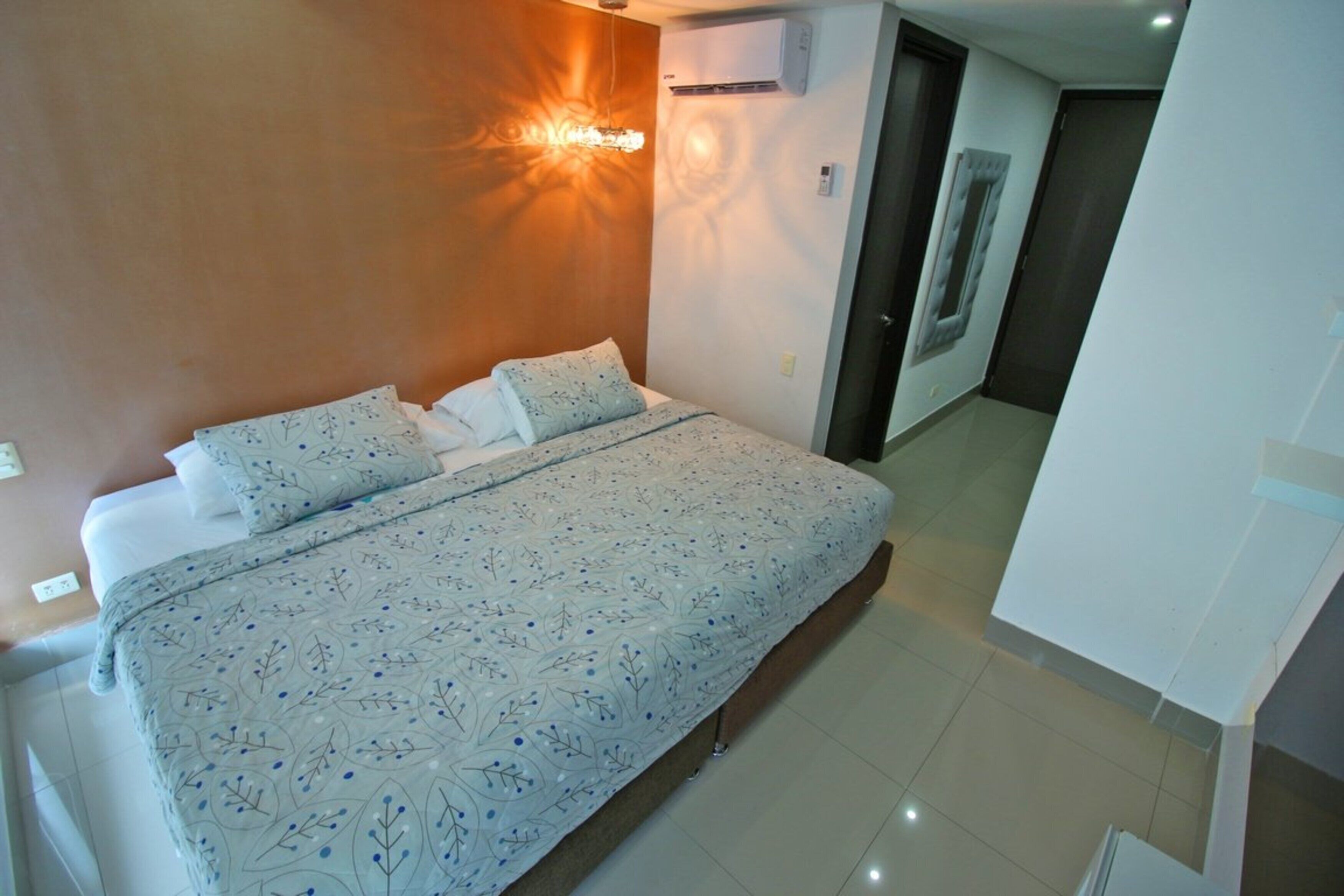 Un dormitorio con una cama grande, una lámpara de pared y un equipo de aire acondicionado.