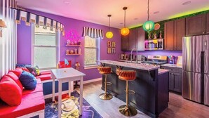 Una cocina moderna con una isla central, taburetes de bar y un letrero de neón.