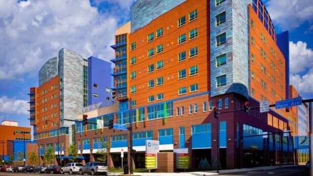 Un hotel de varios pisos con diseño moderno, que presenta una combinación de fachadas de ladrillo y vidrio, ventanas amplias y una entrada destacada en esquina.