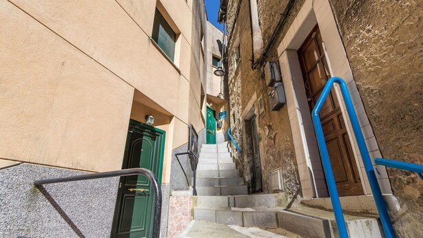 Uma rua estreita com uma escadaria que leva a um edifício com uma porta verde.