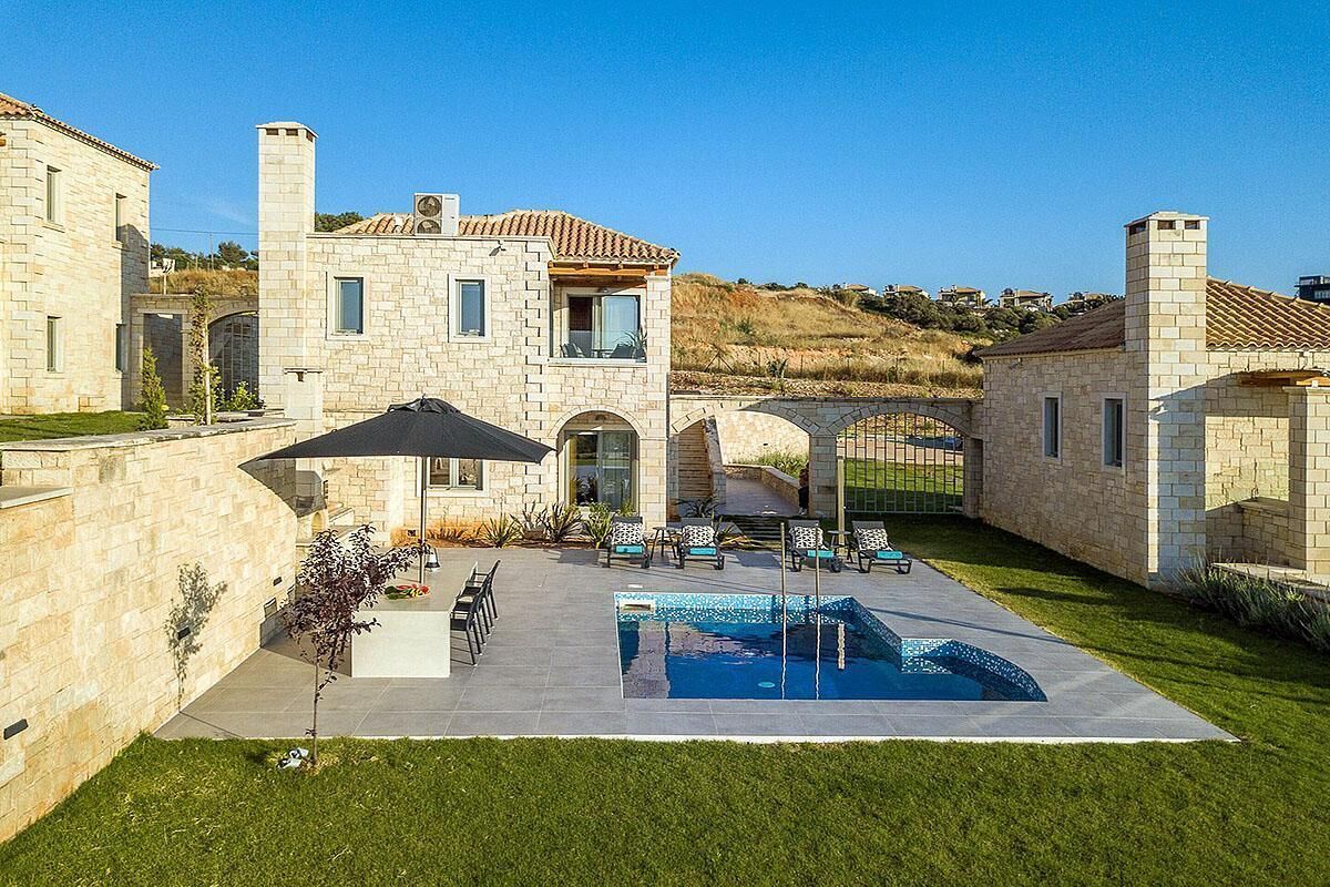 A stone house with a swimming pool, outdoor seating, and a pergola.