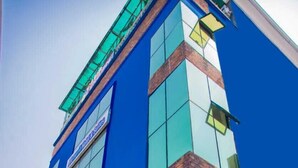 A modern building with a blue facade, large windows, and a brick accent wall. - Blumerrit Hotel & Suites (Lagos)