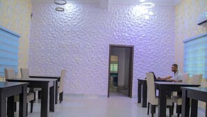 A conference room with a textured white wall, multiple tables, and chairs. - Blumerrit Hotel & Suites (Lagos)