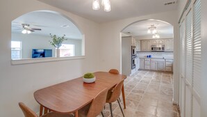 A dining area with a wooden table and chairs, a green decorative bowl, and a ceiling fan.