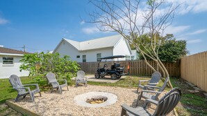 A backyard with a fire pit, Adirondack chairs, and a golf cart.