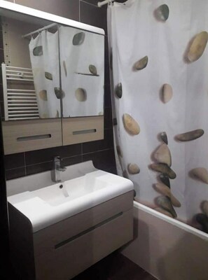A bathroom with a white sink, a mirror above it, and a shower curtain with a stone pattern. - house E. (Hammam Sousse)