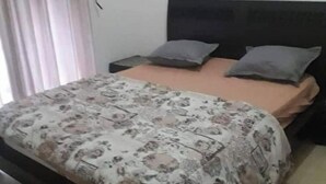 A bedroom with a bed, two pillows, a nightstand, and a wall-mounted picture. - house E. (Hammam Sousse)