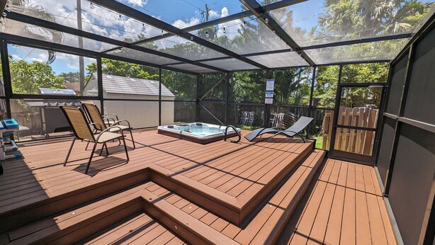 En overdækket terrasse med jacuzzi, træterrasse og liggestole.
