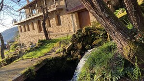 A stone building with a balcony overlooking a stream.