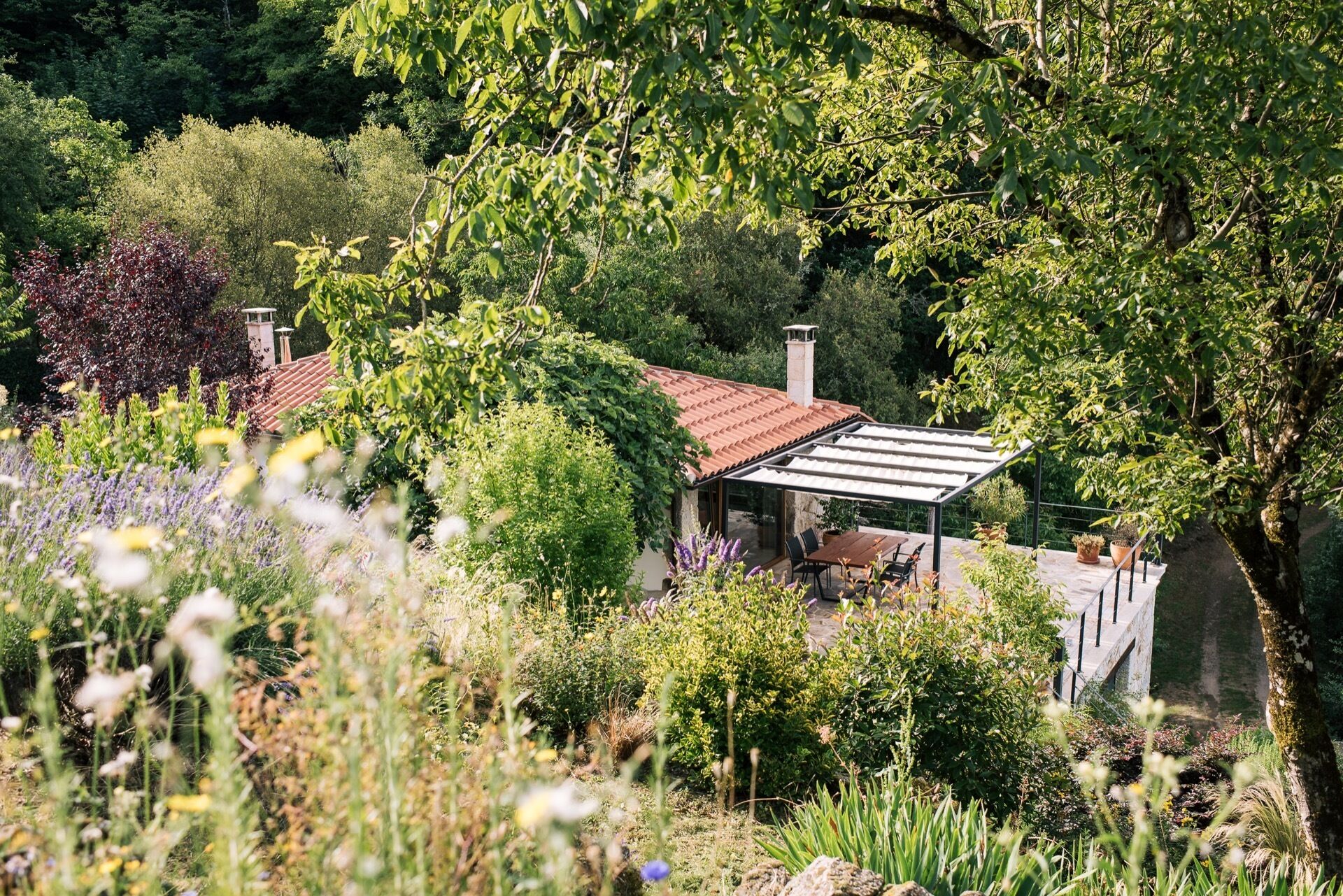 A garden with a patio area, a pergola, and a stone structure.