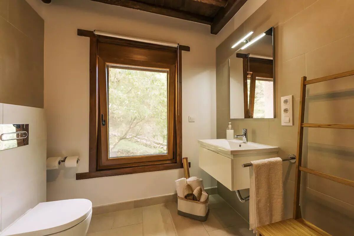 Une salle de bain avec des toilettes, un lavabo et une fenêtre.
