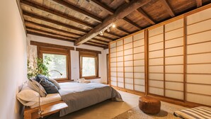 A traditional Japanese-style bedroom with tatami flooring, a low wooden bed, and shoji screens.