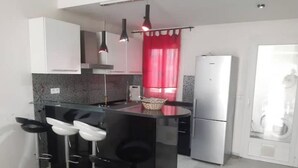 A compact kitchen with a central island, bar stools, a refrigerator, and a washing machine. - House F. (Hammam Sousse)