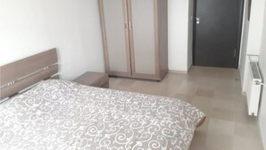 A bedroom with a bed, a wardrobe, a nightstand, and a door. - House F. (Hammam Sousse)