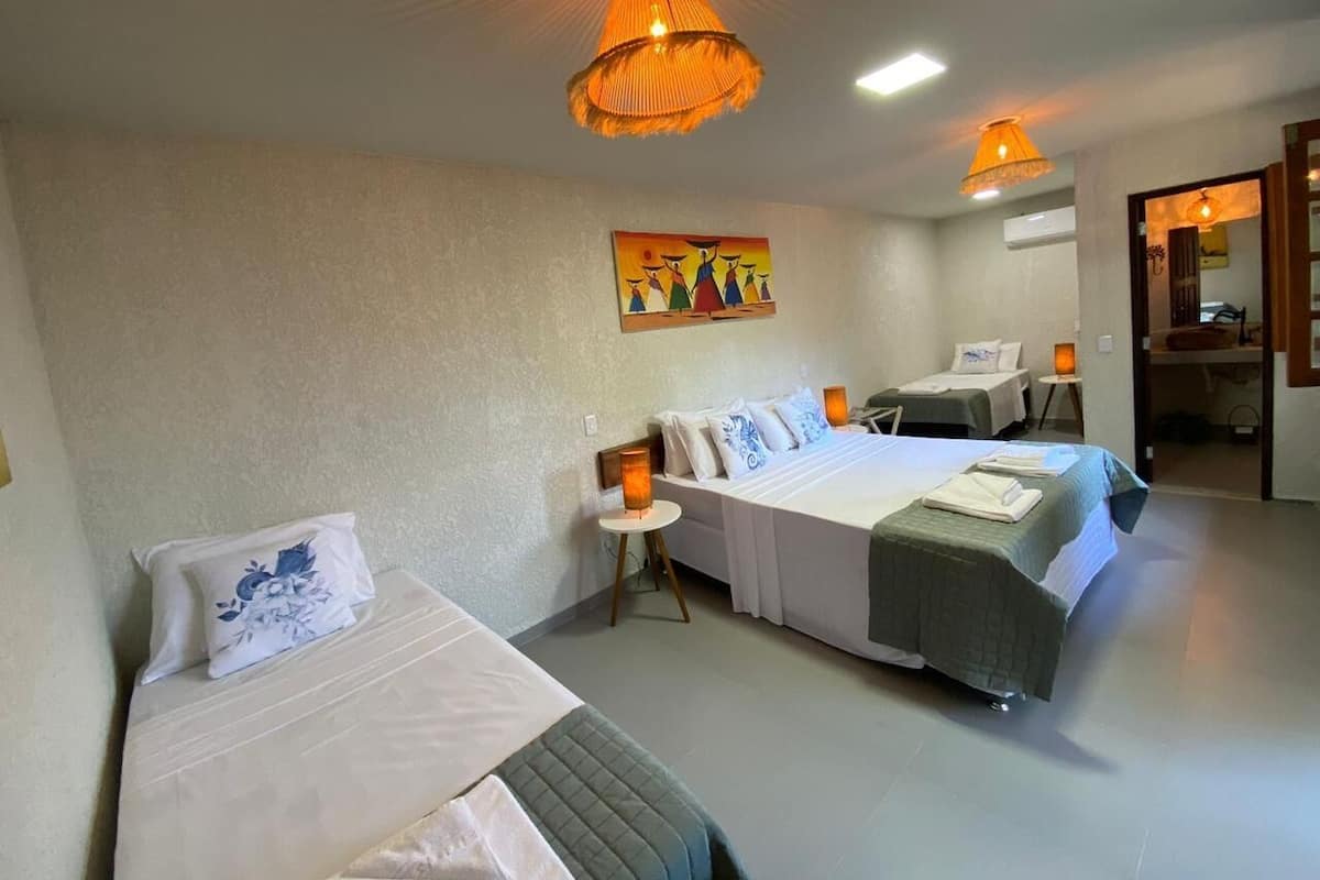 Habitación de hotel con dos camas, una mesita y un cuadro en la pared.