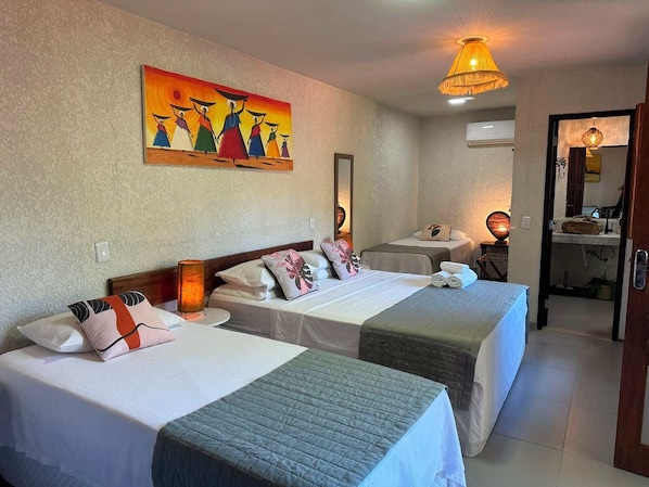 A hotel room with two beds, a painting on the wall, a mirror, and a door leading to a bathroom.