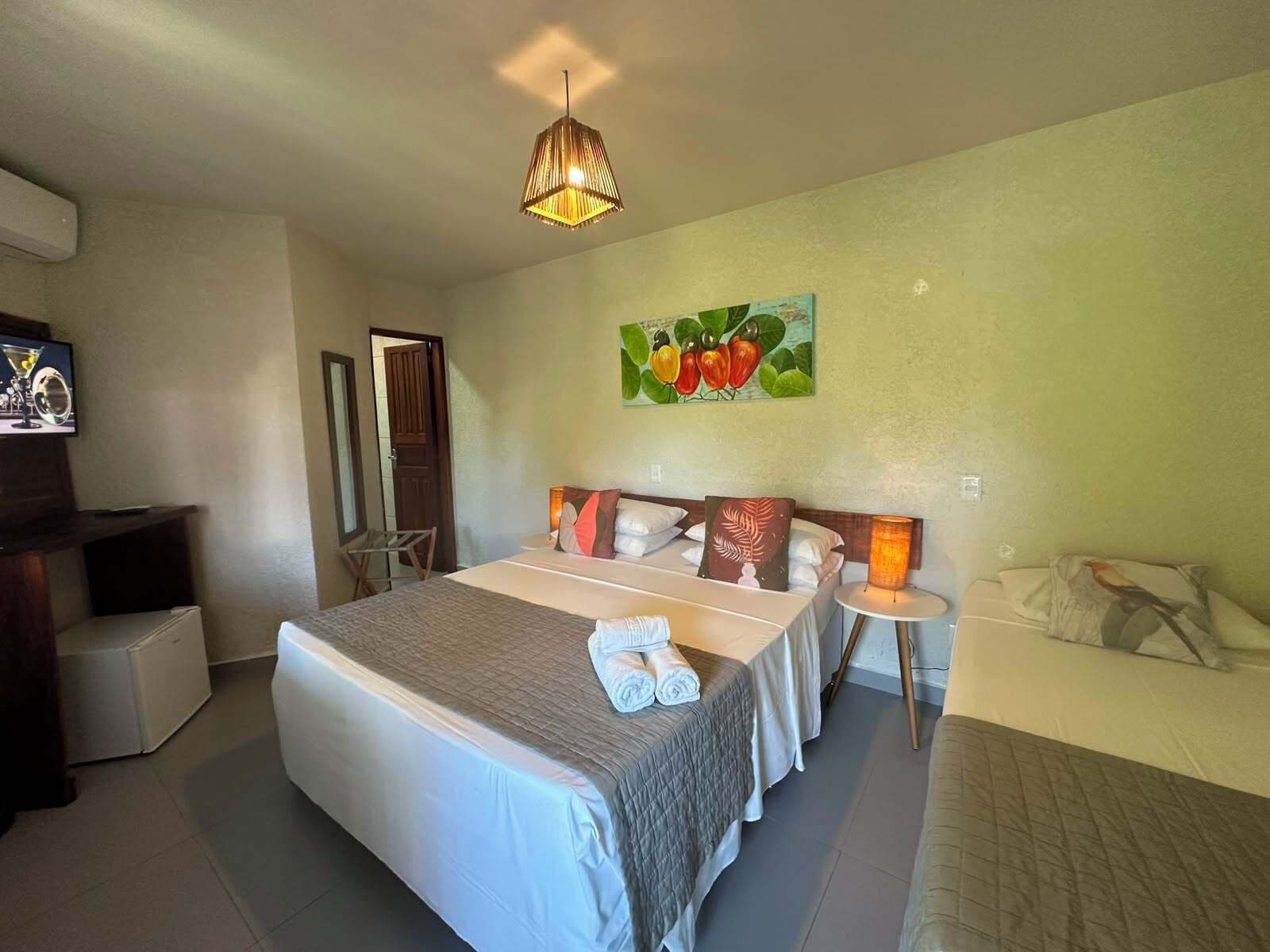 Ein Hotelzimmer mit Bett, Nachttischen, Fernseher, einem Gemälde und einer Lampe.