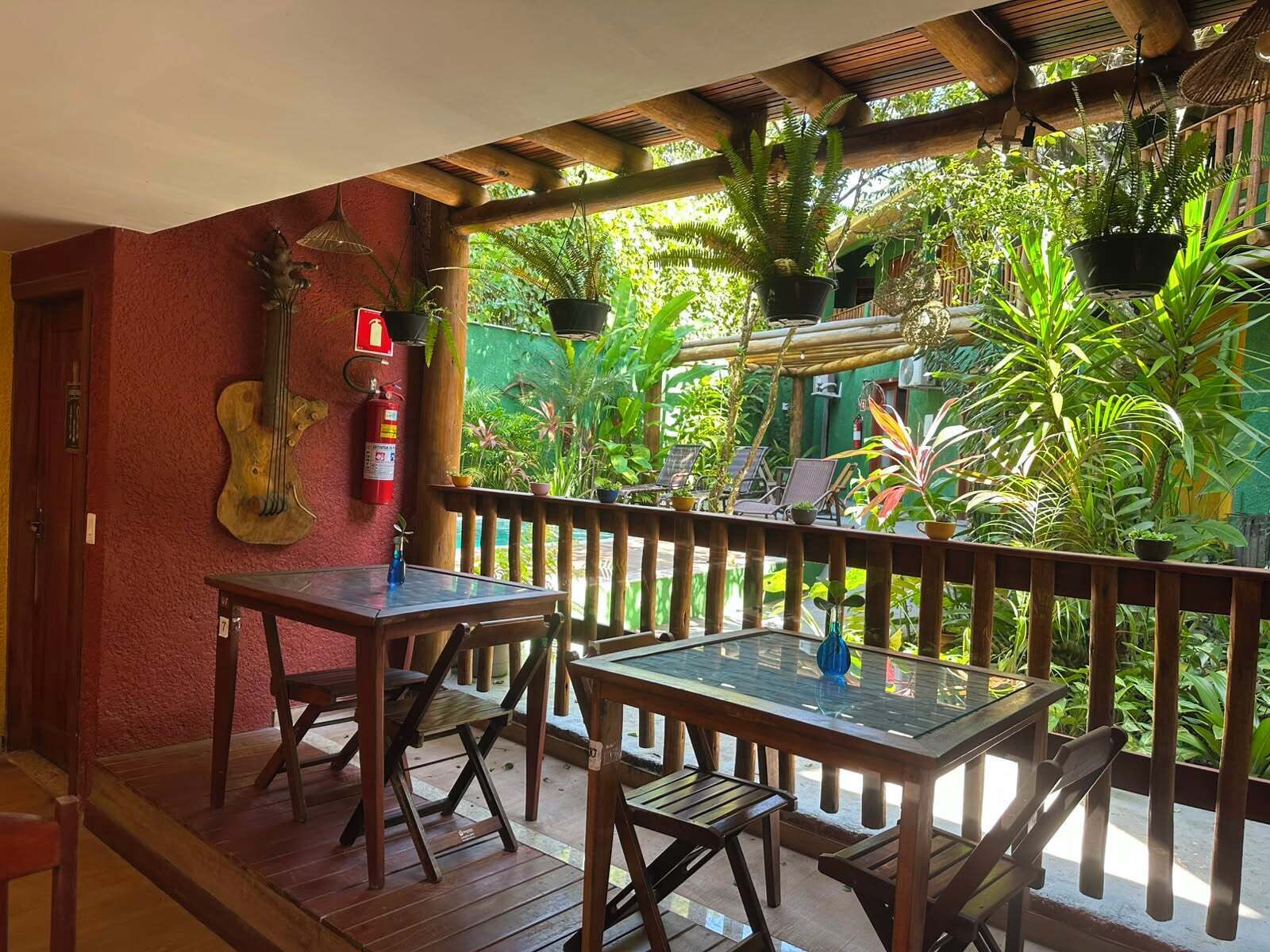 A wooden table and chairs on a veranda with a view of lush greenery.