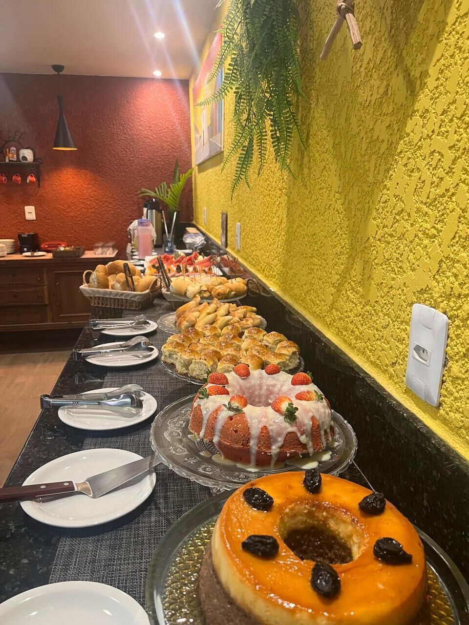 Un buffet con diversi dolci e una parete gialla dalla texture particolare.