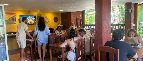 A restaurant with wooden tables and chairs, a counter, and a mural on the wall.