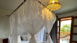 Een slaapkamer met een hemelbed, een plafondlamp en uitzicht op de omgeving.