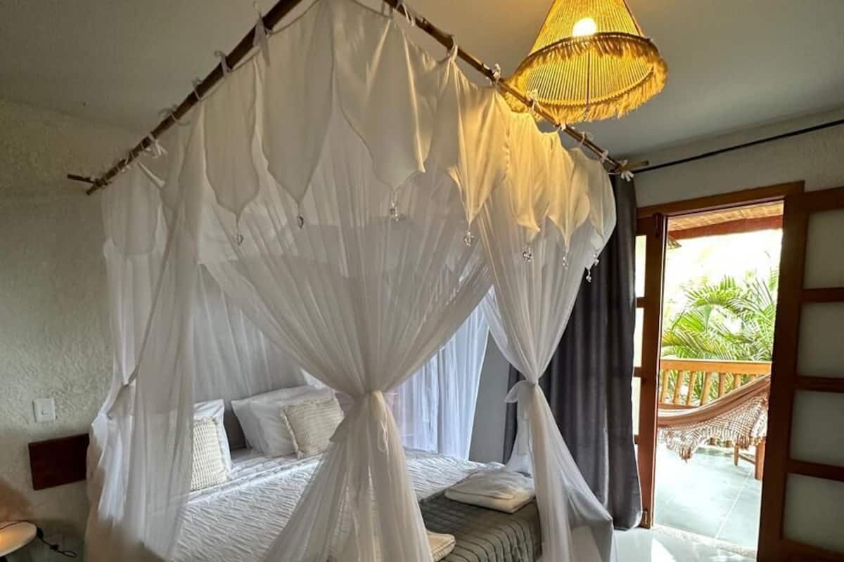 Un dormitorio con cama con dosel, una lámpara de techo y vistas al exterior.