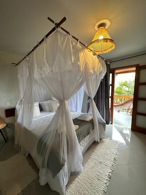 A bedroom with a canopy bed, a ceiling lamp, and a view of the outdoors. - Pousada Preciosa do Arraial - com Natura e L’Occitane - recém inaugurada (Porto Seguro)
