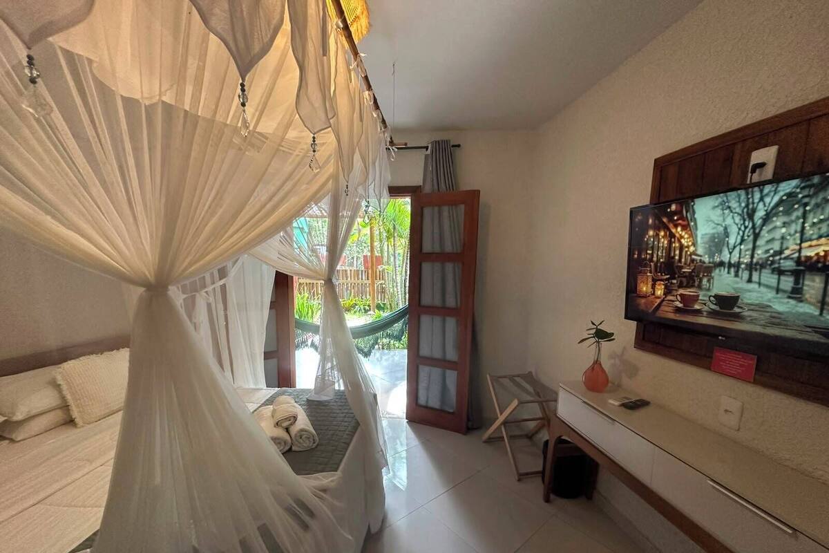 Un dormitorio con cama con dosel, un televisor en la pared y vistas al exterior.