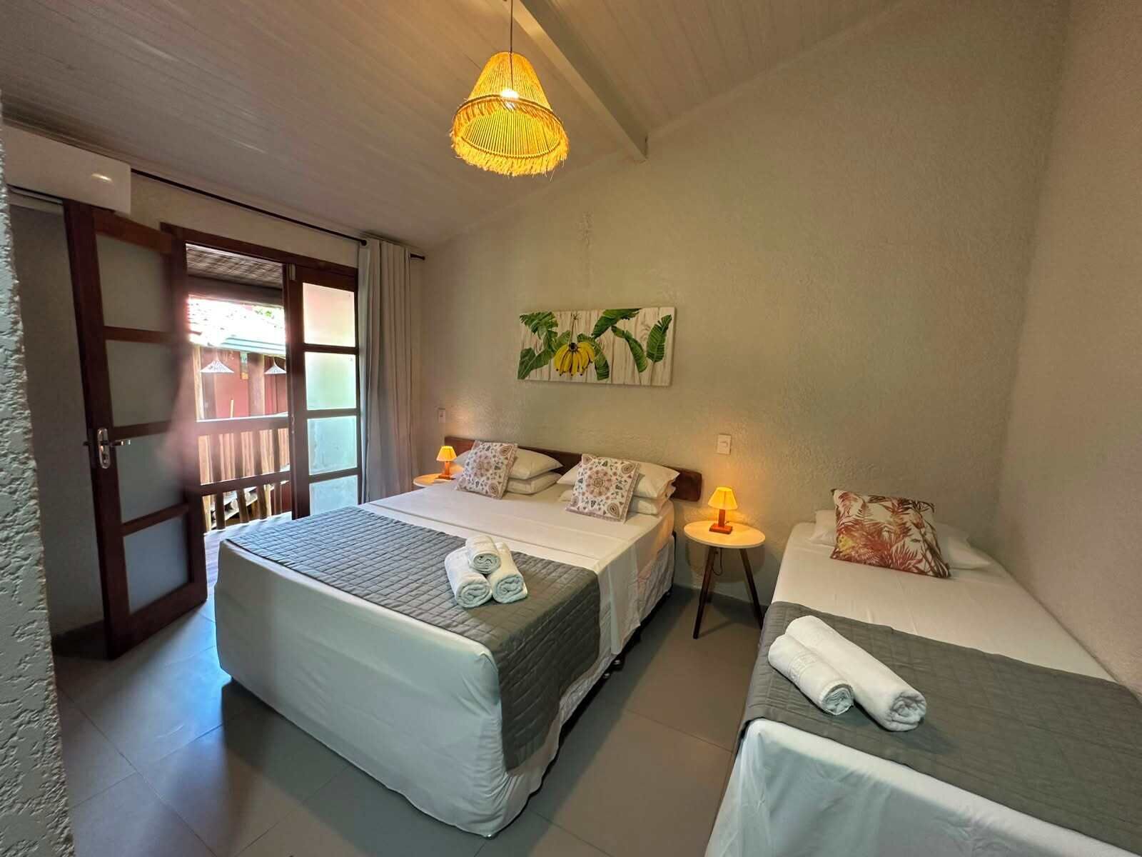 Habitación de hotel con dos camas, una puerta que da al exterior, una mesita con una lámpara y un aplique.