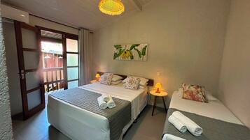 Habitación de hotel con dos camas, una puerta que da al exterior, una mesita con una lámpara y un aplique.
