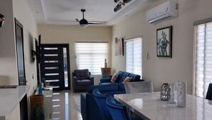 Une cuisine moderne avec un coin repas, comprenant un plan de travail en marbre, des chaises recouvertes de tissu bleu et un ventilateur de plafond.