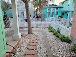 Stroll along the stone-paved pathway to a charming neighborhood with beautifully maintained homes and lush greenery.