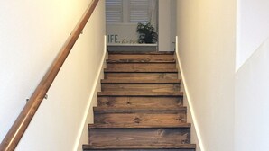 Una escalera de madera con barandilla que conduce a una plataforma con una planta y un cartel que dice 'life happy'.