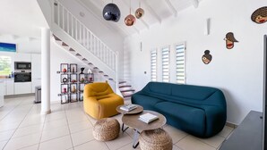 En moderne stue med trappe, sofa, sofabord og et køkken i baggrunden.