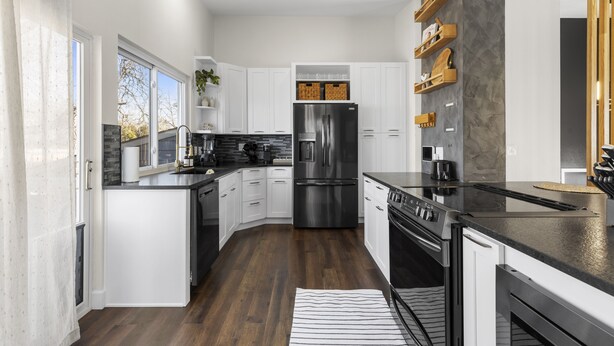 A modern kitchen with white cabinetry, a stainless steel refrigerator, and a black countertop. - Modern Close to Denver 4bdr Home-Great for groups (Arvada)