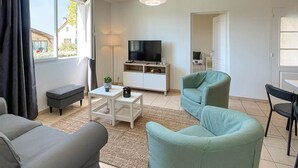 Een moderne woonkamer met een bank, een salontafel, een televisie en een klein kastje.