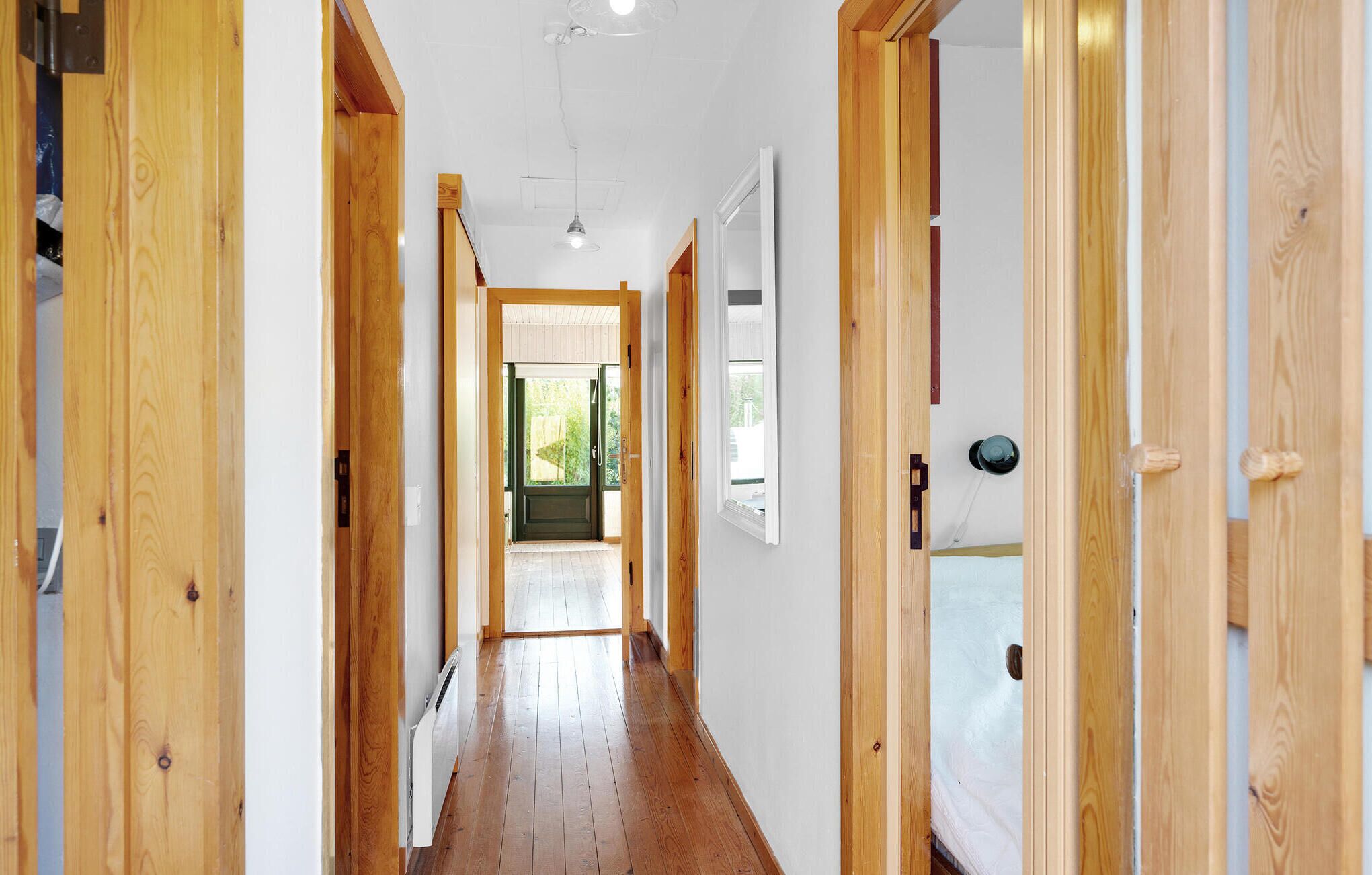 A wooden hallway with a door at the end leading to a room with a window.